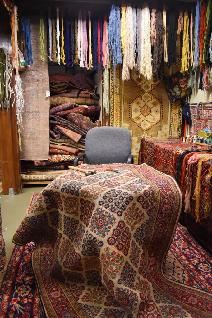 Handmade rug restoration workshop with yarns and repair tools